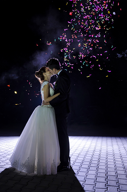 grooms kissing in love grooms kissing surrounded by colorful confetti.